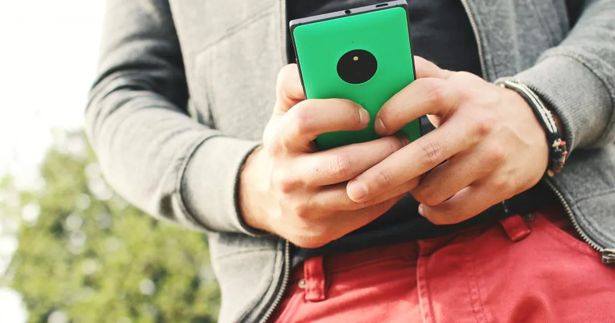 Persona escribiendo un mensaje en un celular de carcasa verde