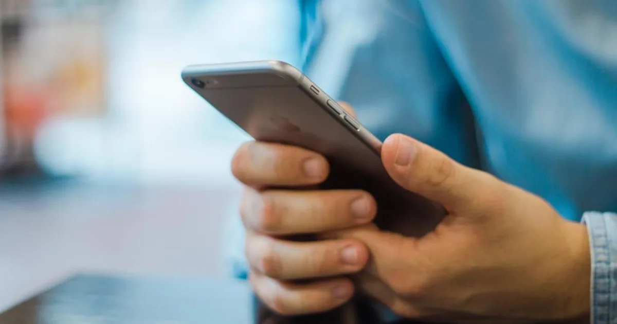 Manos sosteniendo un smartphone para revisar mensajes en la pantalla