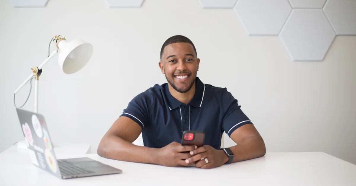 Emprendedor sonriente en su escritorio con laptop y celular