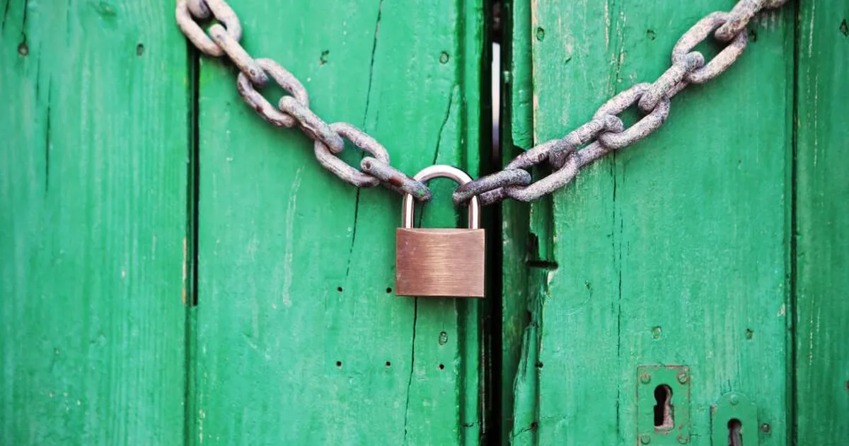 Cadena con candado cerrando una puerta de madera verde, símbolo de protección