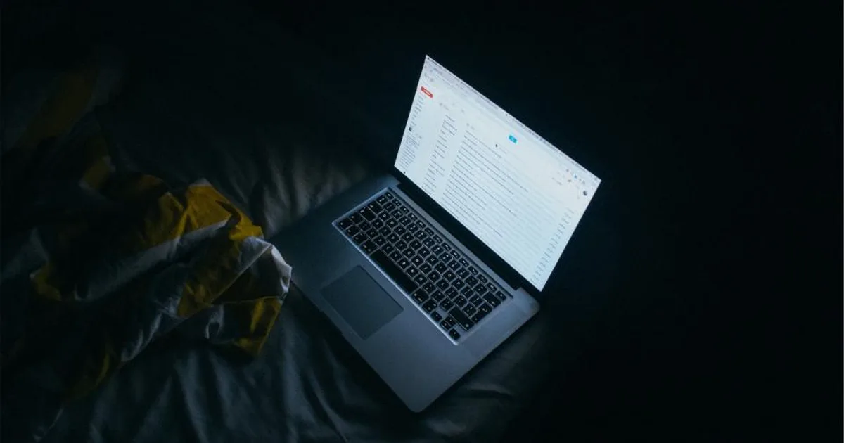 Laptop abierta en la oscuridad mostrando una bandeja de entrada de correo