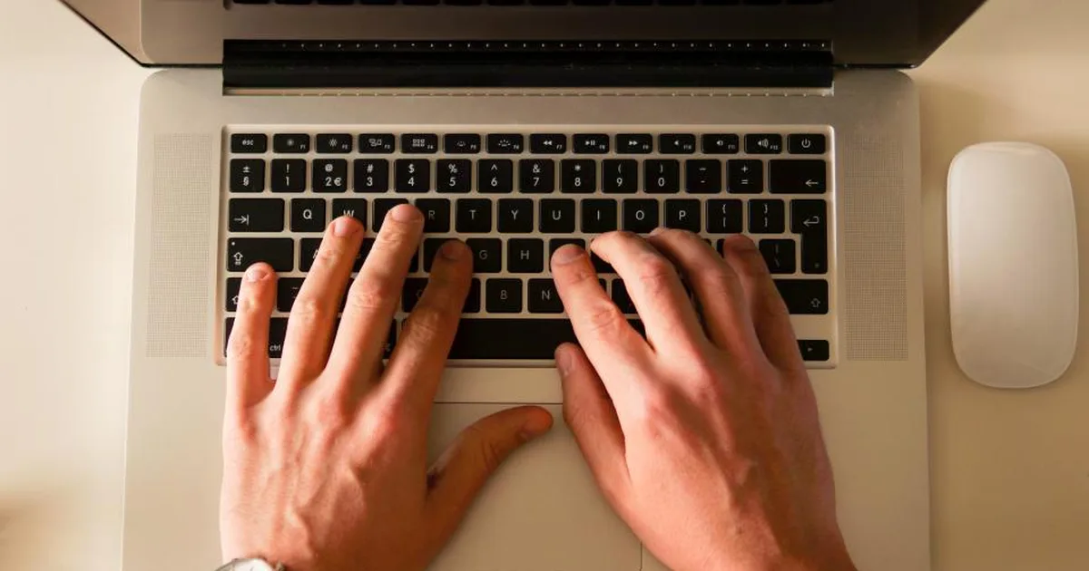 Manos escribiendo en el teclado de una laptop vista desde arriba