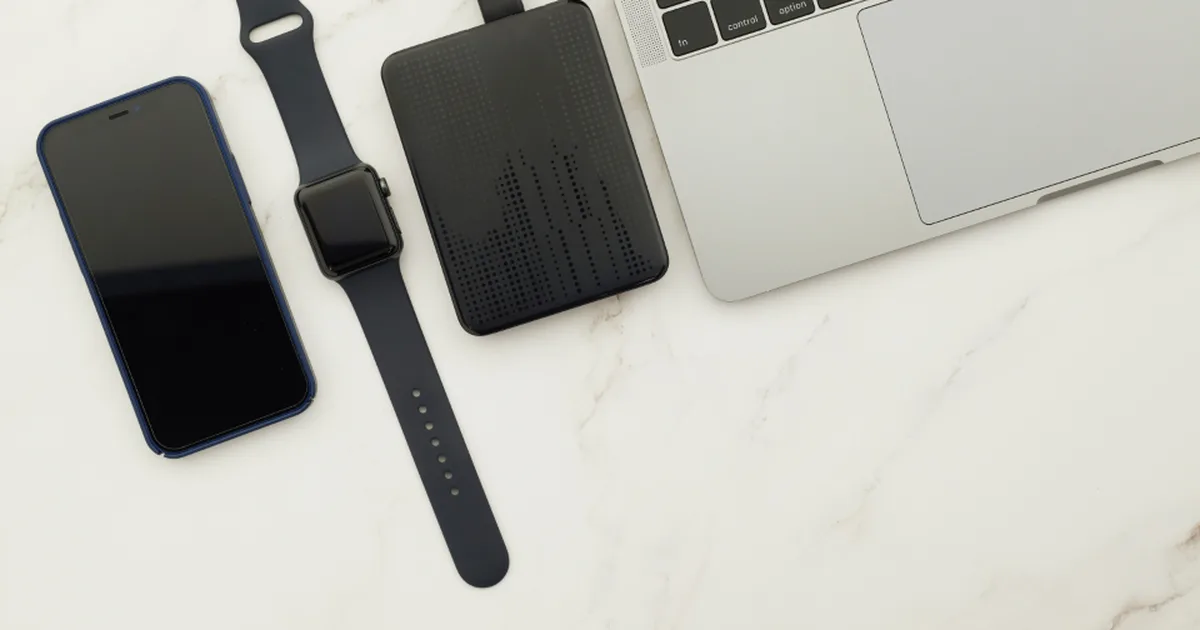 Disco duro externo junto a una laptop, un celular y un reloj inteligente