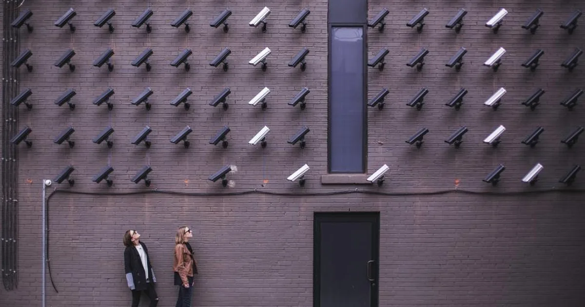 Pared cubierta de cámaras de seguridad que vigilan a dos personas