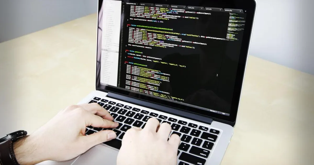 Manos escribiendo código en una laptop con un editor de programación abierto