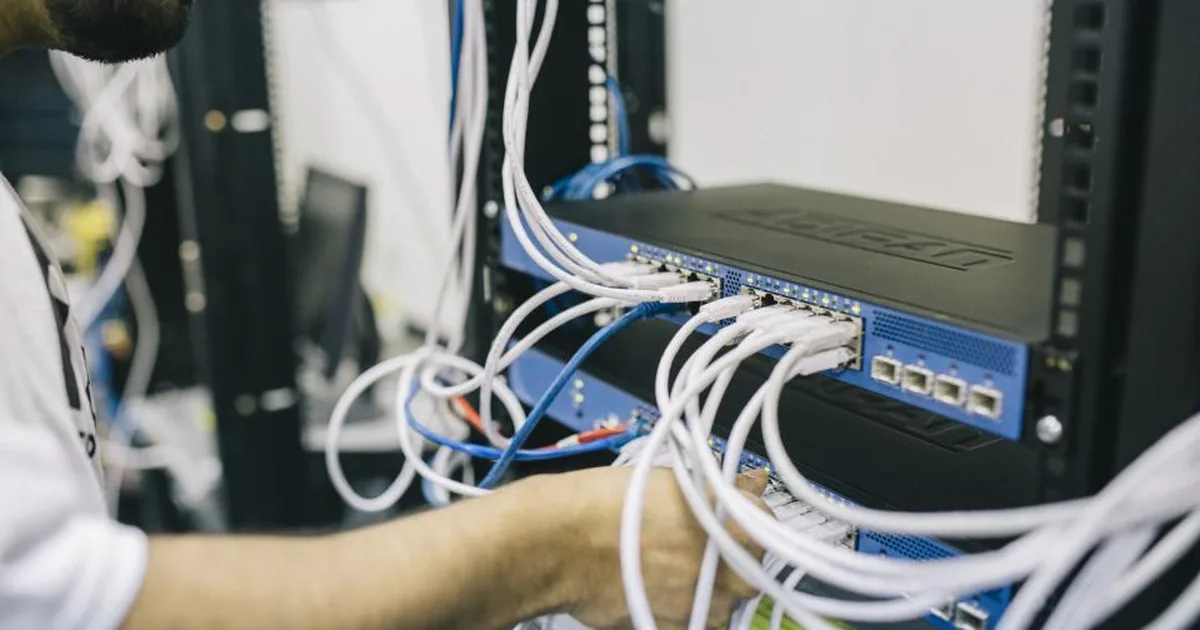 Técnico conectando cables de red a un switch en un rack de servidores
